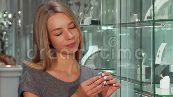 年轻女子微笑着试着戴钻戒在珠宝店购物视频的预览图