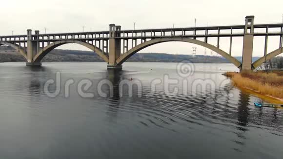 美丽的宽阔的河面上有一座巨大的桥人们坐着独木舟漂浮在河底视频的预览图