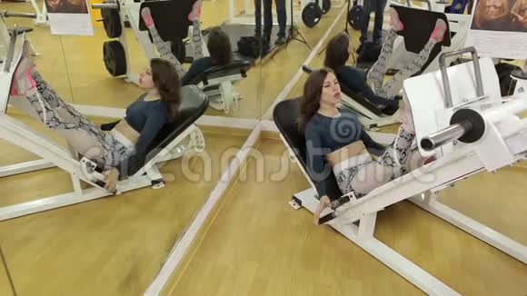 一个女孩在健身房训练她的腿的肌肉她让腿部按压躺下视频的预览图