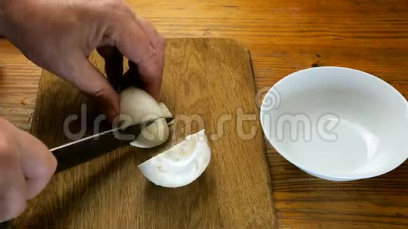 人用手用菜刀将香菜菇切在木厨房板上视频的预览图