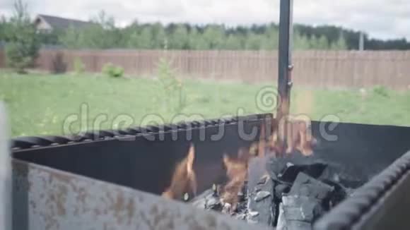 在绿色草地背景下关闭营地火焰和烧烤行动在金属里燃烧木柴和灰烬视频的预览图