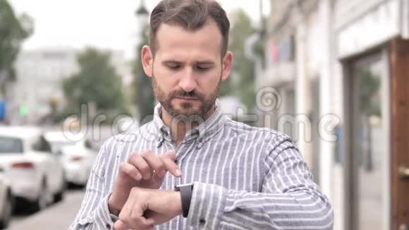 胡子休闲男子使用智能手表户外视频的预览图