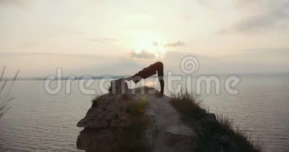 年轻女子在海边的大石头上做晨练视频的预览图