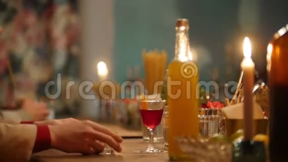 专业的酒保在酒吧里用柔和的室内灯光将橙色饮料倒入一个小玻璃杯中视频的预览图