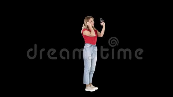 年轻漂亮的女人用睫毛膏看手机阿尔法频道视频的预览图