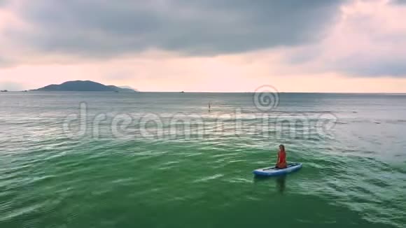 靠岸的女孩坐在海边的桨板上视频的预览图