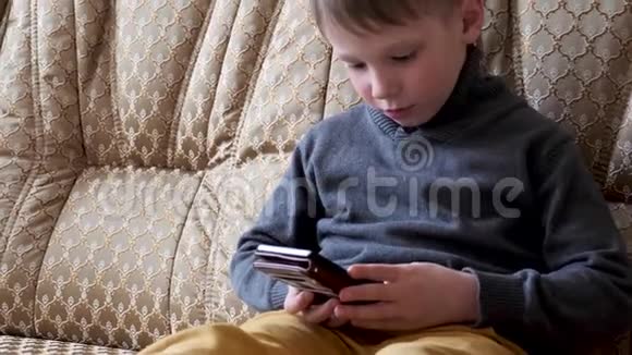 小男孩坐在沙发上打电话视频的预览图