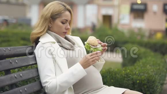 准妈妈吃有害汉堡坐公园高脂肪营养垃圾食品视频的预览图
