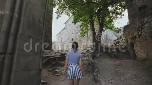 女孩在格鲁吉亚高地的一座教堂周围的古代防御堡垒中行走视频的预览图