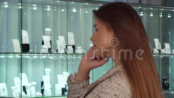 年轻的女顾客微笑着在奢侈品店挑选珠宝出售视频的预览图