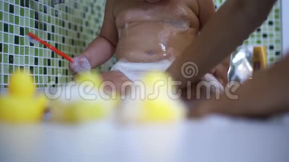 可爱的蹒跚学步的女孩在浴室刷牙可爱的宝宝坐在水槽里视频的预览图
