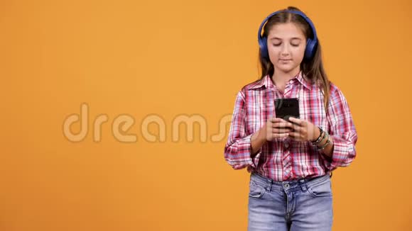 年轻漂亮的女孩一边听音乐一边看智能手机视频的预览图