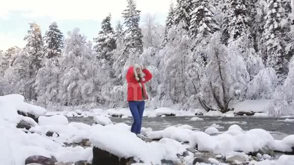 这位妇女在一条山河的河岸上享受着一个寒冷的冬天的早晨呼吸着寒冷的空气快乐着视频的预览图