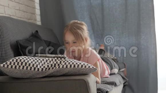 十几岁的女孩玩平板电脑躺在家里的沙发上人技术和休闲理念视频的预览图