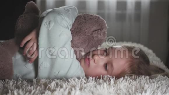 一个悲伤的少女和泰迪熊躺在床上的肖像视频的预览图
