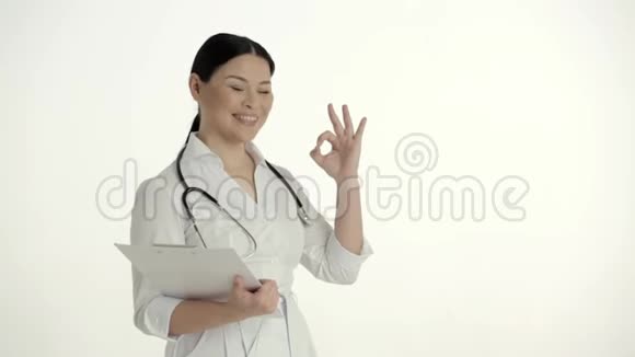 白色背景的亚洲护士微笑着举起拇指视频的预览图