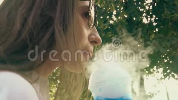 在炎热的夏日里一位正在抽烟的年轻女子喝着蓝色干冰视频的预览图