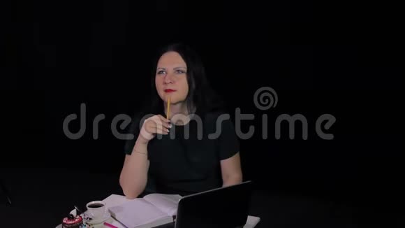 一个在咖啡馆的桌子旁沉思的女人在电脑旁工作喝咖啡视频的预览图