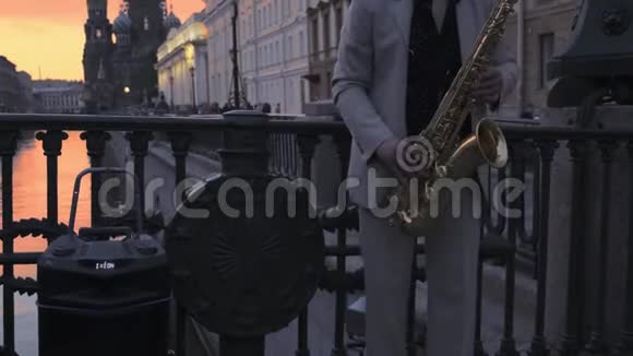 萨克斯演奏者穿着轻便的西装在夕阳下的桥上演奏萨克斯风视频的预览图