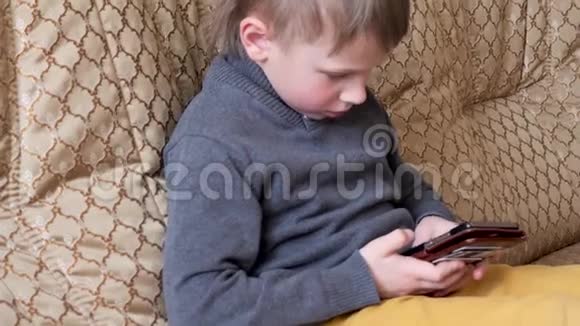 小男孩坐在沙发上打电话视频的预览图