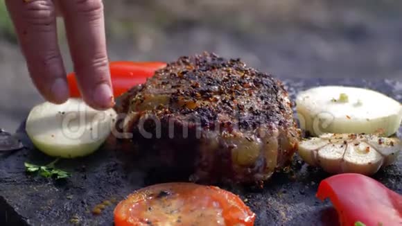 提供野餐开胃的多汁牛排在篝火上煎炸并在烟雾特写中加入香料和蔬菜视频的预览图