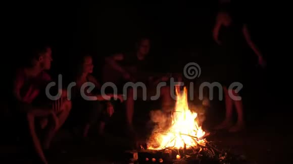 漂亮的女人在篝火旁跳舞她的朋友们在晚上唱歌鼓掌视频的预览图