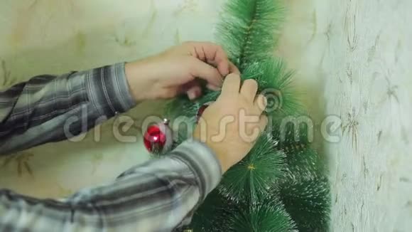 男人手用喜庆的球装饰圣诞树视频的预览图