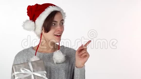 戴着圣诞帽的快乐美女拿着礼物指着copyspace视频的预览图