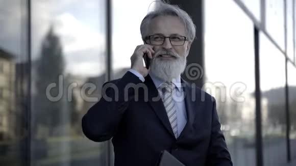 英俊的白种人高级CEO使用智能手机和智能平板电脑视频的预览图