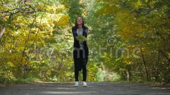 美丽的年轻女孩在公园里扔树叶享受着幸福自由休闲理念秋天放松的女人视频的预览图