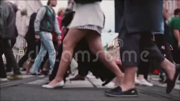 美丽的慢动作镜头人们的腿和脚穿过一条繁忙的老城区街道中间有电车轨道视频的预览图