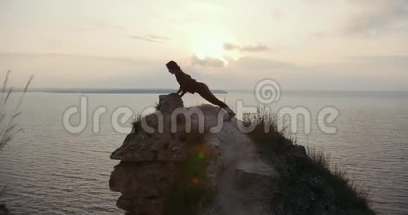 年轻女子在海边的大石头上热身视频的预览图
