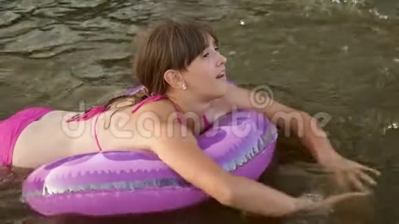 年轻漂亮的女孩正在一个充气圈的水里游泳女孩微笑着视频的预览图