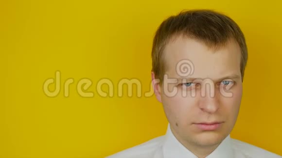黄墙背景上戴着黑眼镜的白衬衫严肃男人的肖像视频的预览图