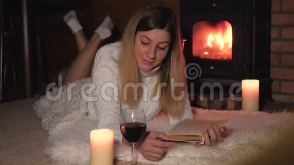 女人躺在壁炉边的毯子上喝酒读书视频的预览图