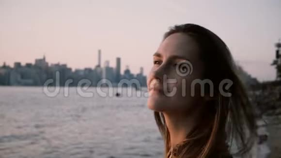 特写照片年轻美丽的欧洲女孩看日落然后在大城市河流4K附近的相机摆姿势视频的预览图