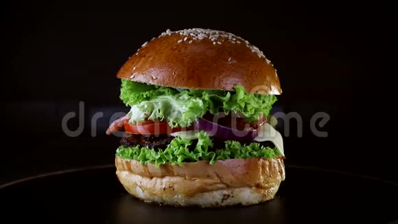 汉堡有一个切块和炒鸡蛋覆盖绿色旋转在木板上黑色背景视频的预览图