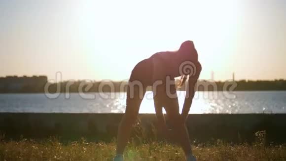 运动女性在日落时在水边跑步前训练身体视频的预览图
