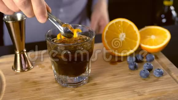 巴曼把橘子和蓝莓放进酒精鸡尾酒里放在石头玻璃上用吸管双手特写视频的预览图