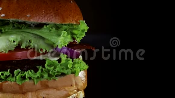 汉堡有一个切块和炒鸡蛋覆盖绿色旋转在木板上从黑色的背景视频的预览图