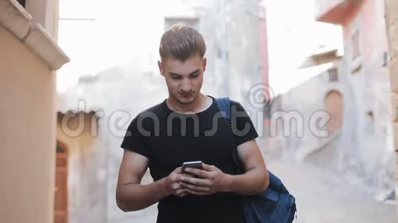 年轻人在旧城散步使用智能手机男性与朋友聊天视频的预览图