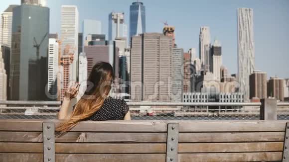 快乐女旅行者的后视图头发随风飘扬享受着纽约的天际线张开双臂视频的预览图