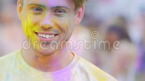 微笑的年轻人在彩色粉末显示拇指庆祝霍利节视频的预览图