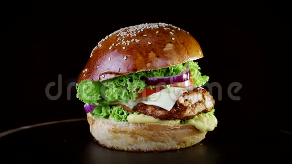 快餐有烤排骨青菜番茄和洋葱的汉堡在黑色背景的木板上慢慢旋转视频的预览图