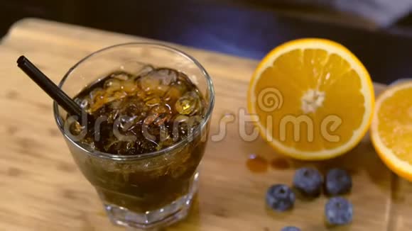酒保用蓝莓和橘子的香味在岩石玻璃上装饰鸡尾酒手特写视频的预览图