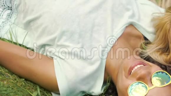 活泼开朗的女学生躺在草地上用电话看照片面带微笑视频的预览图
