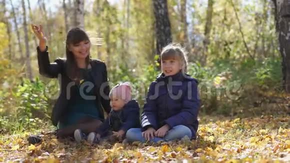 在一个阳光明媚的秋日带着孩子的妈妈的小家庭在公园里感到寒冷慢动作3840x21604K视频的预览图
