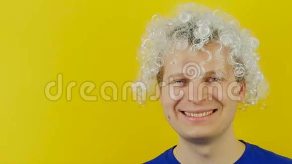 白色的头发卷曲的微笑着戴着黑色太阳镜的男人在黄色的墙壁背景上有趣而愉快的人类情感视频的预览图