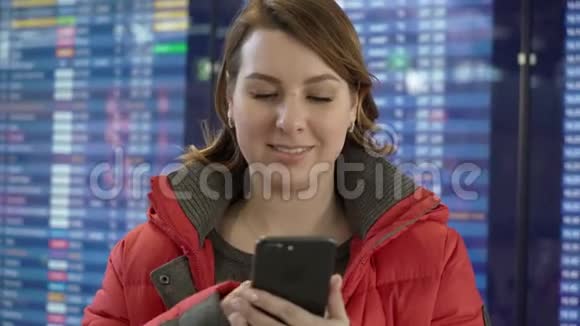 女人拿着手机在机场看信息板视频的预览图