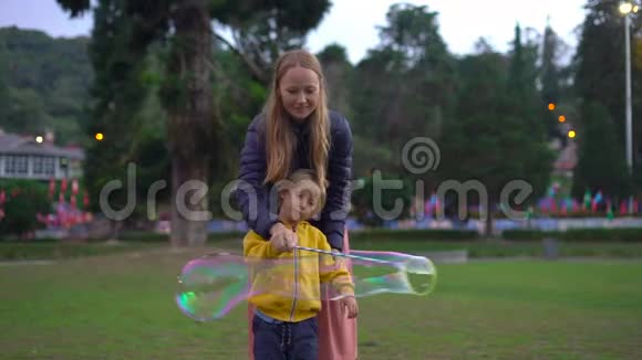 一个女人和她的小儿子在公园里做一个大肥皂泡的慢镜头视频的预览图